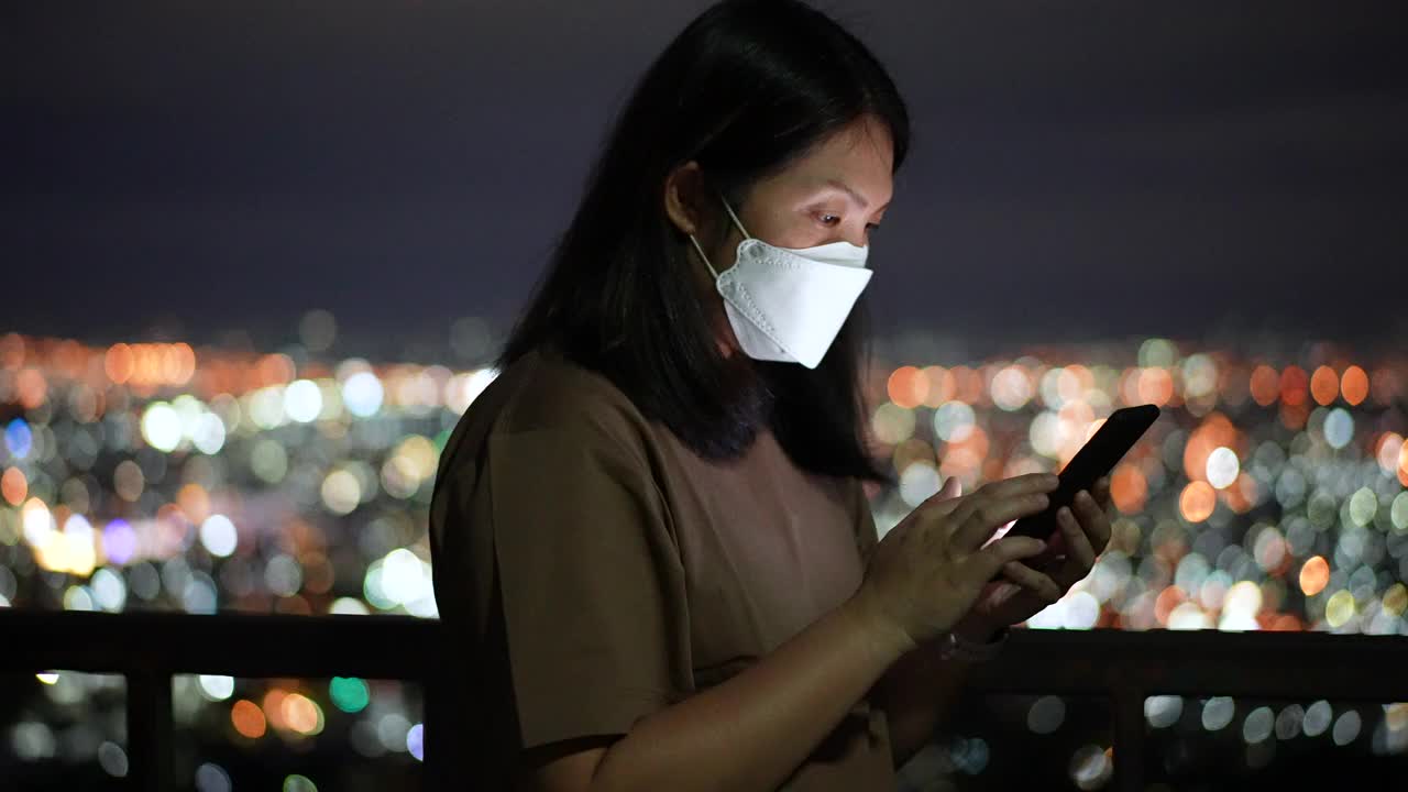 女人在夜里用手机用圆灯散景在城里视频素材