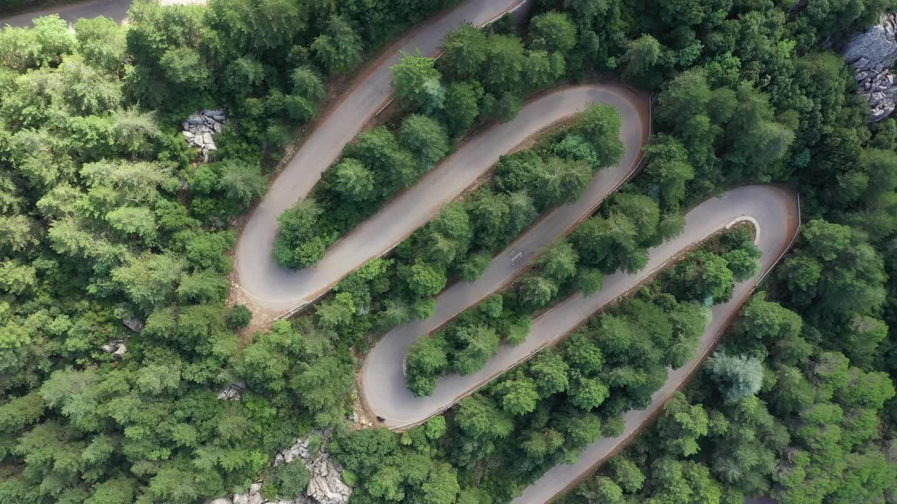 从上面看，令人惊叹的鸟瞰图，一辆汽车沿着蜿蜒的道路运行，周围是绿色的松树。林巴拉山(蒙特林巴拉)撒丁岛，意大利视频素材