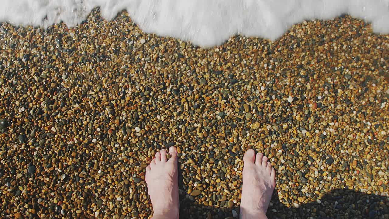 海浪打在赤脚的人身上视频素材