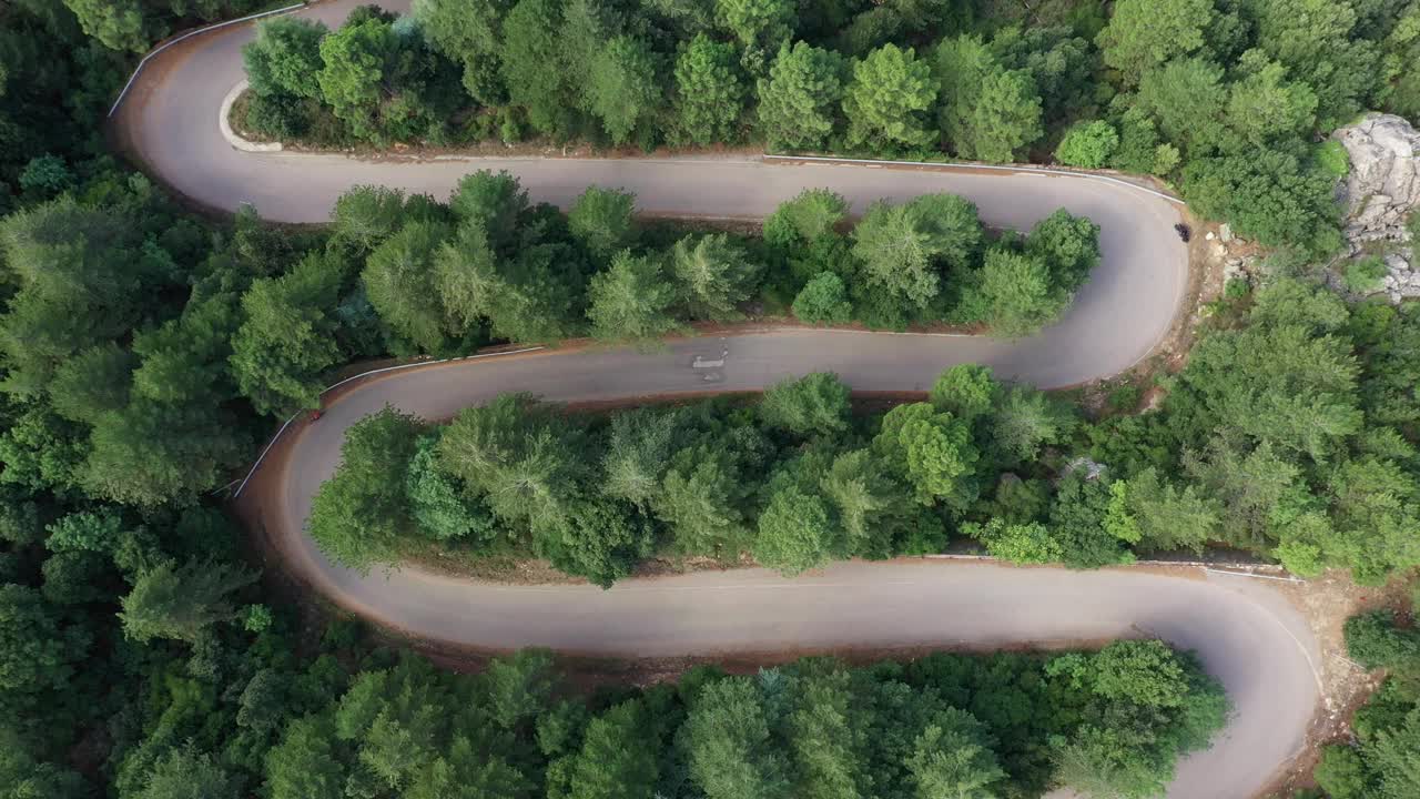 从上面看，令人惊叹的鸟瞰图，一辆汽车沿着蜿蜒的道路运行，周围是绿色的松树。林巴拉山(蒙特林巴拉)撒丁岛，意大利视频素材