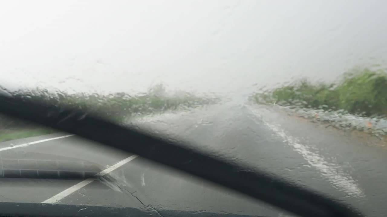 车的观点行驶在下雨的公路和挡风玻璃雨刷擦雨视频素材