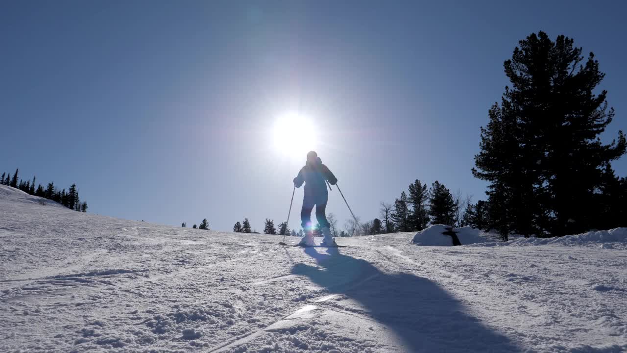 剪影滑雪者在雪坡上滑雪在山区度假胜地在阳光明媚的冬日视频素材