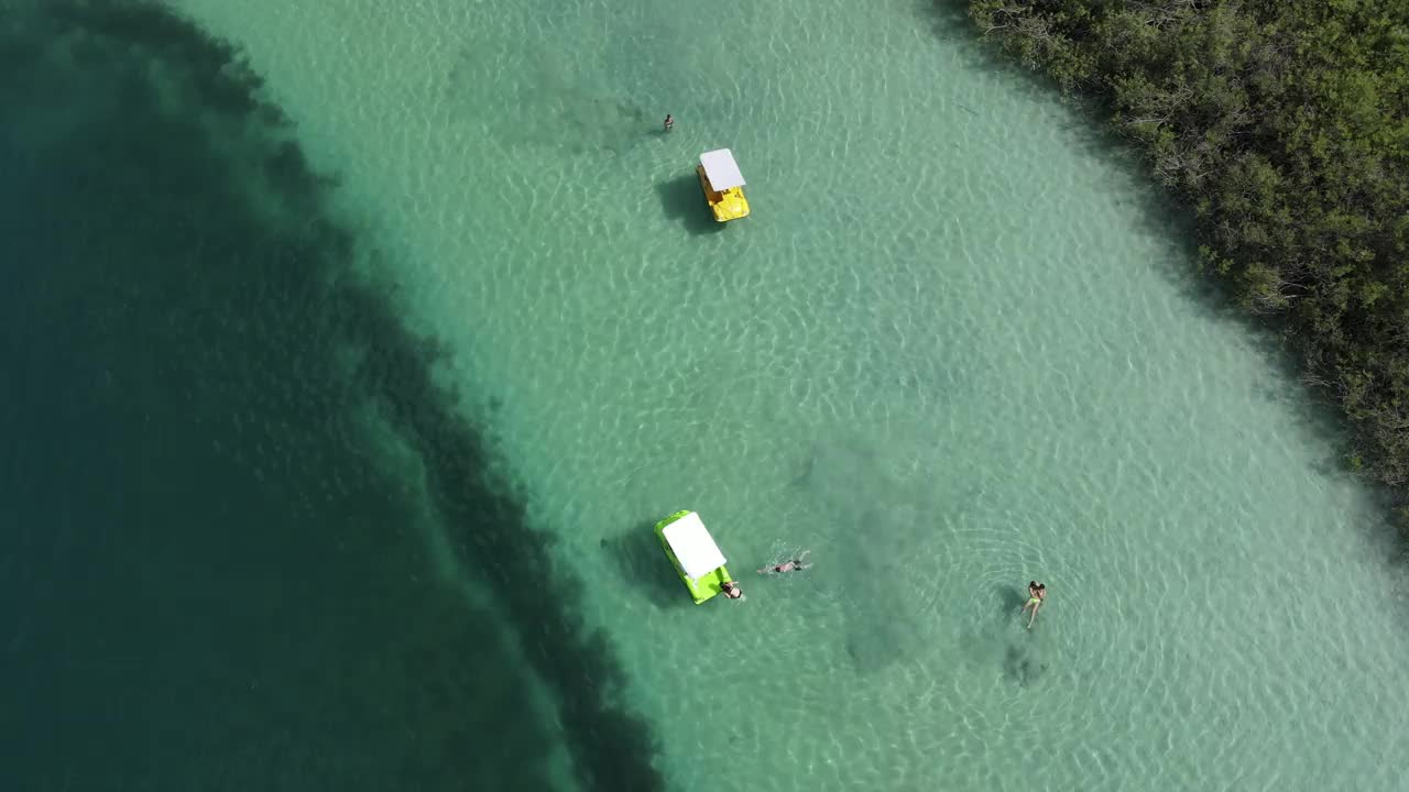 无人机拍摄湖，漂浮的双体船和游泳的人以岸为背景。视频素材