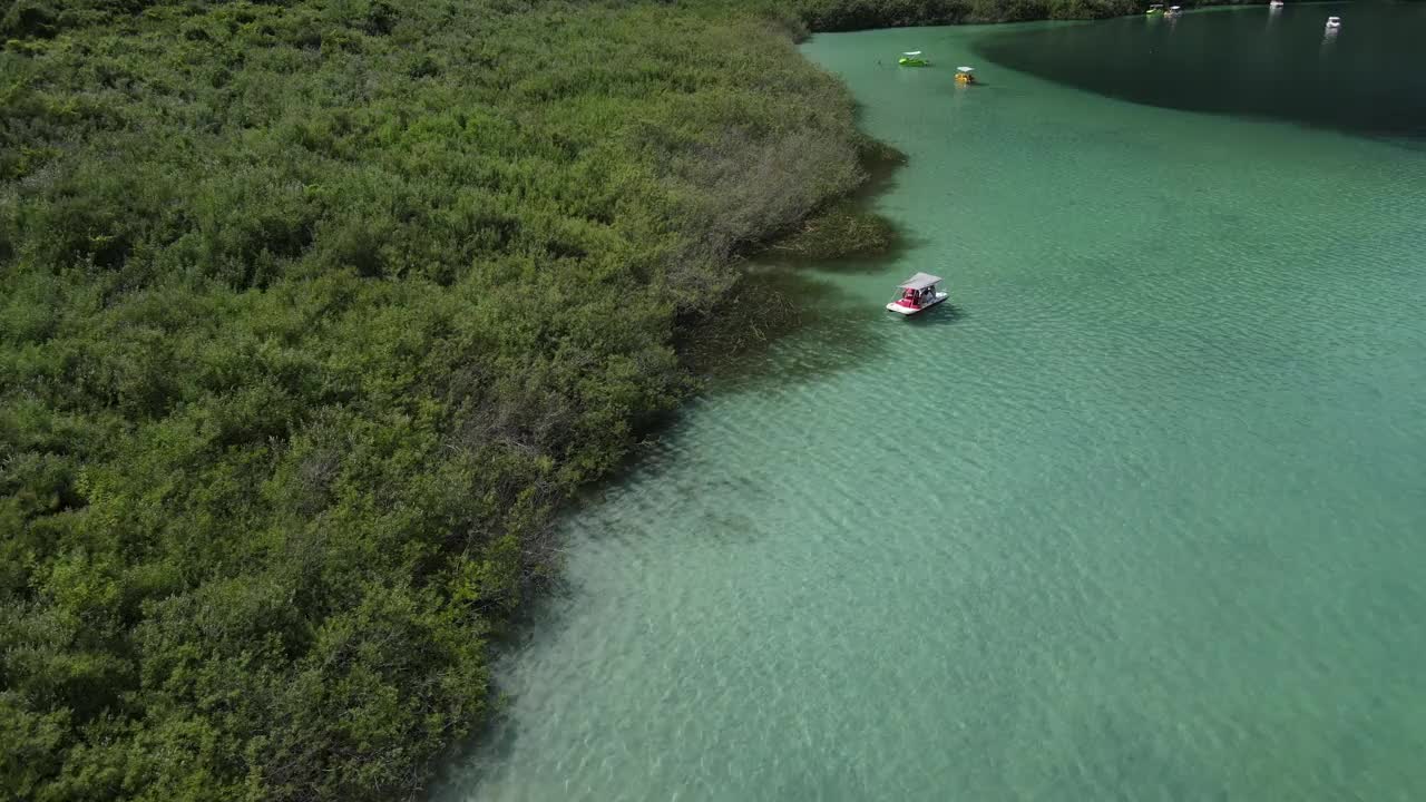 无人机拍摄湖，漂浮的双体船和游泳的人以岸为背景。视频素材