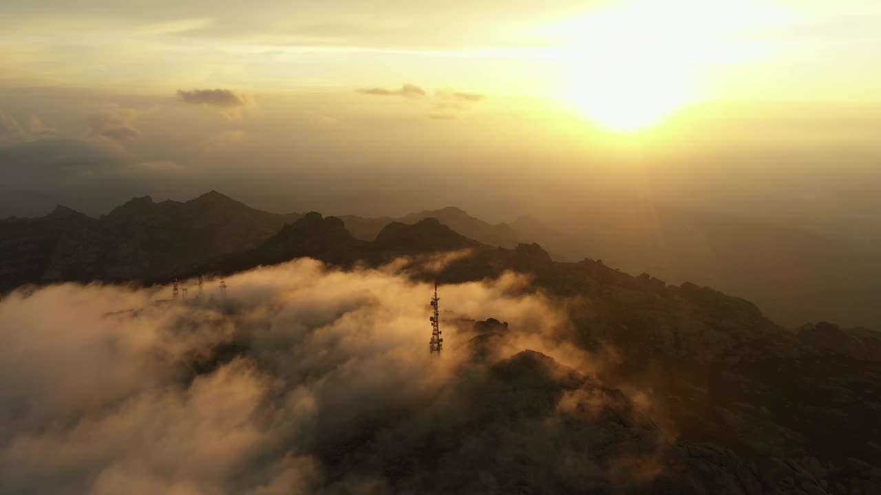 从上面看，鸟瞰图的山脉与天线农场包围移动的云在一个惊人的日出。林巴拉山(蒙特林巴拉)撒丁岛，意大利。视频素材