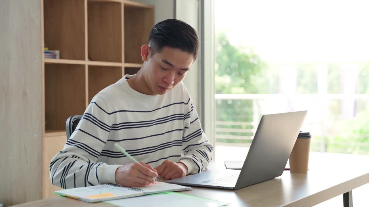 年轻的亚洲学生在家里用笔记本电脑打视频电话。视频素材