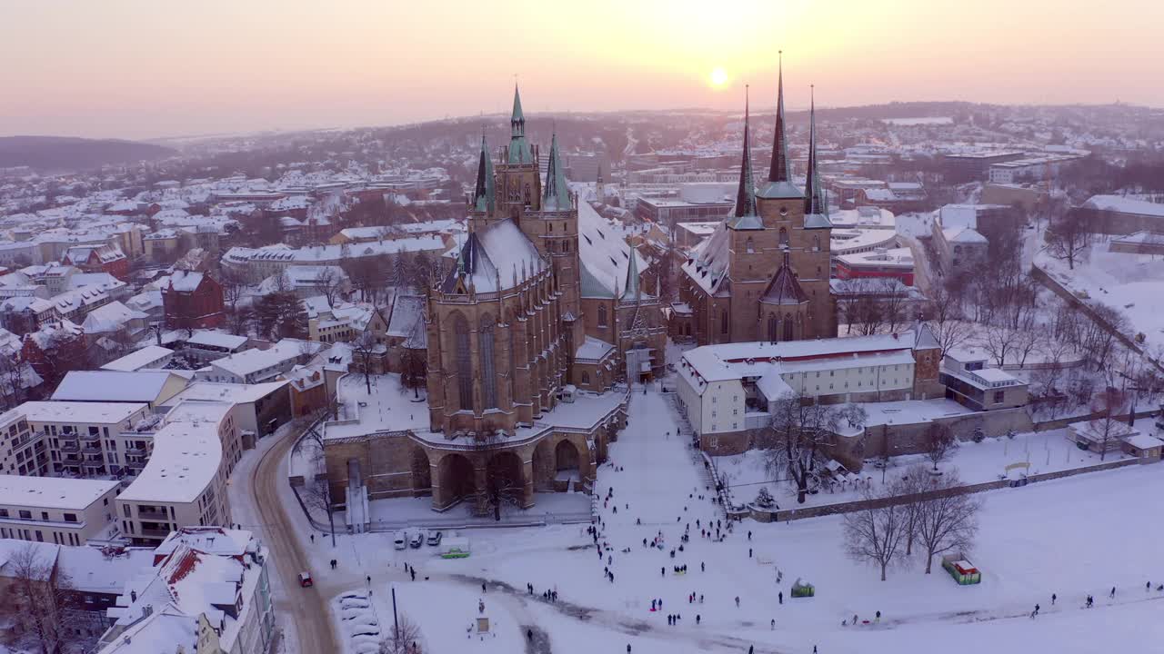 航拍:在城市中著名的大教堂和住宅，无人机在日落时飞过雪景-埃尔福特，德国视频素材