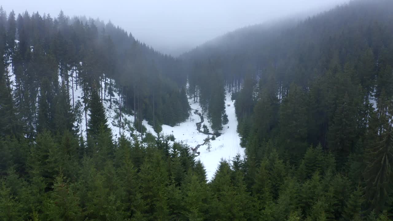 航拍:美丽的拍摄汽车移动的雪景，无人机下降在流动的河流在森林-埃尔福特，德国视频素材