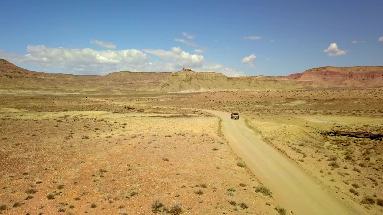 航拍:越野车在沙漠的道路上移动，无人机在阳光明媚的日子飞越半干旱的景观-页，亚利桑那州视频素材