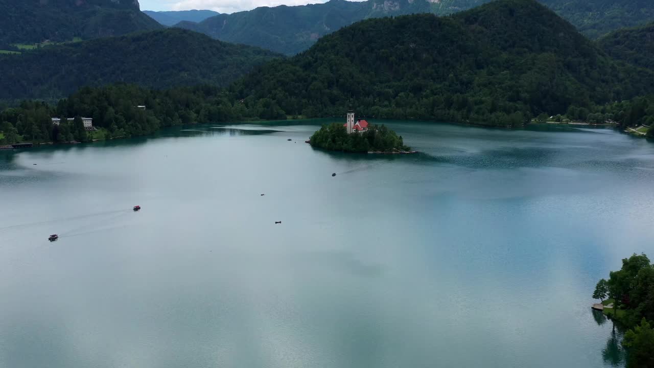 从空中俯瞰岛上美丽的古老教堂，船只在湖中移动-布莱德，斯洛文尼亚视频素材