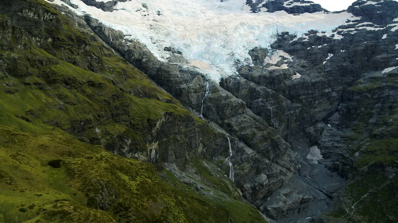 鸟瞰图:雪山流水的美丽景色，直升机飞过绿色植物-奥克兰，新西兰视频素材