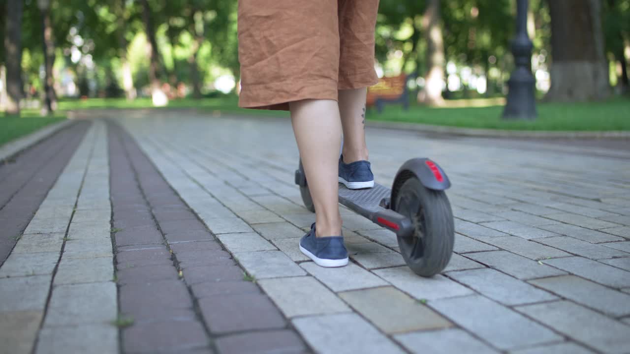 年轻女子在城市公园骑电动车，环保交通工具视频素材