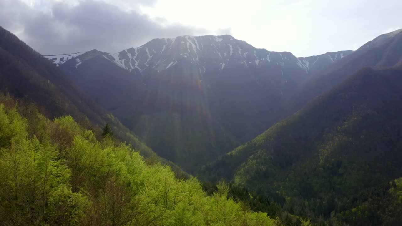 空中风景的雪山在多云的天空，无人机飞行向上越过绿色森林-亚平宁山脉，意大利视频素材