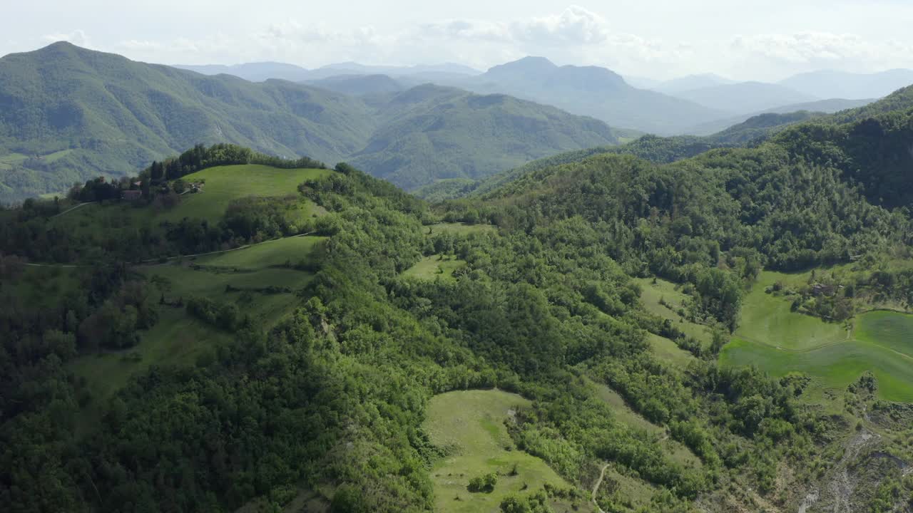 空中拍摄的绿色山脉对多云的天空，无人机飞过森林-亚平宁山脉，意大利视频素材