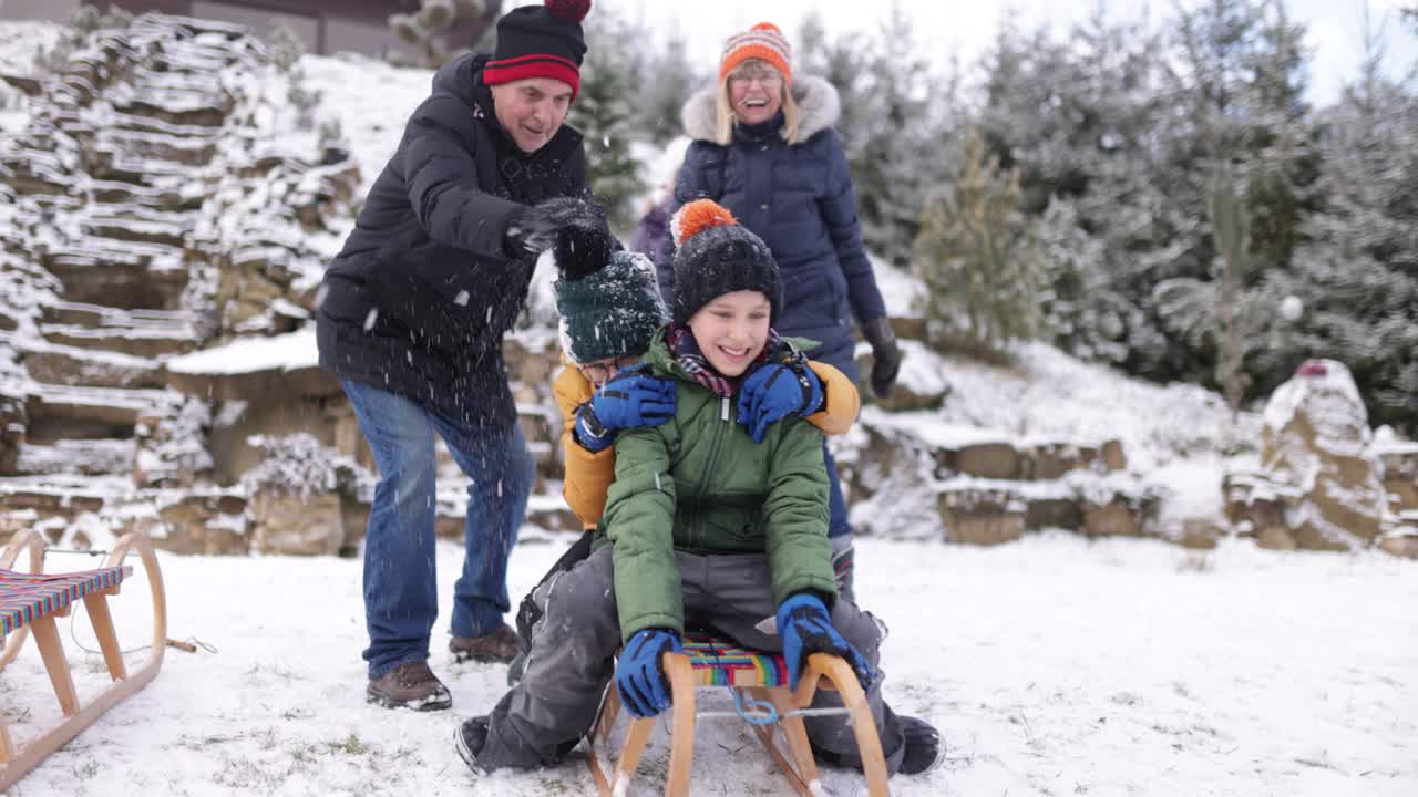 冬天的一天，爷爷奶奶和孙子孙女们在后院玩雪橇视频素材