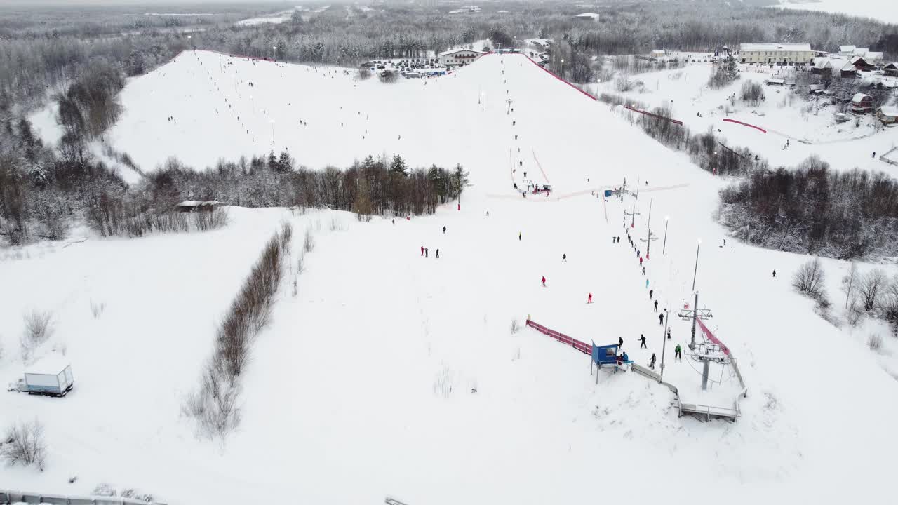 在滑雪胜地，无人机在索道上的全景俯视图。滑雪电梯运送滑雪者和滑雪板运动员在雪山度假村的冬季斜坡上，许多人。UHD 4 k的视频视频素材