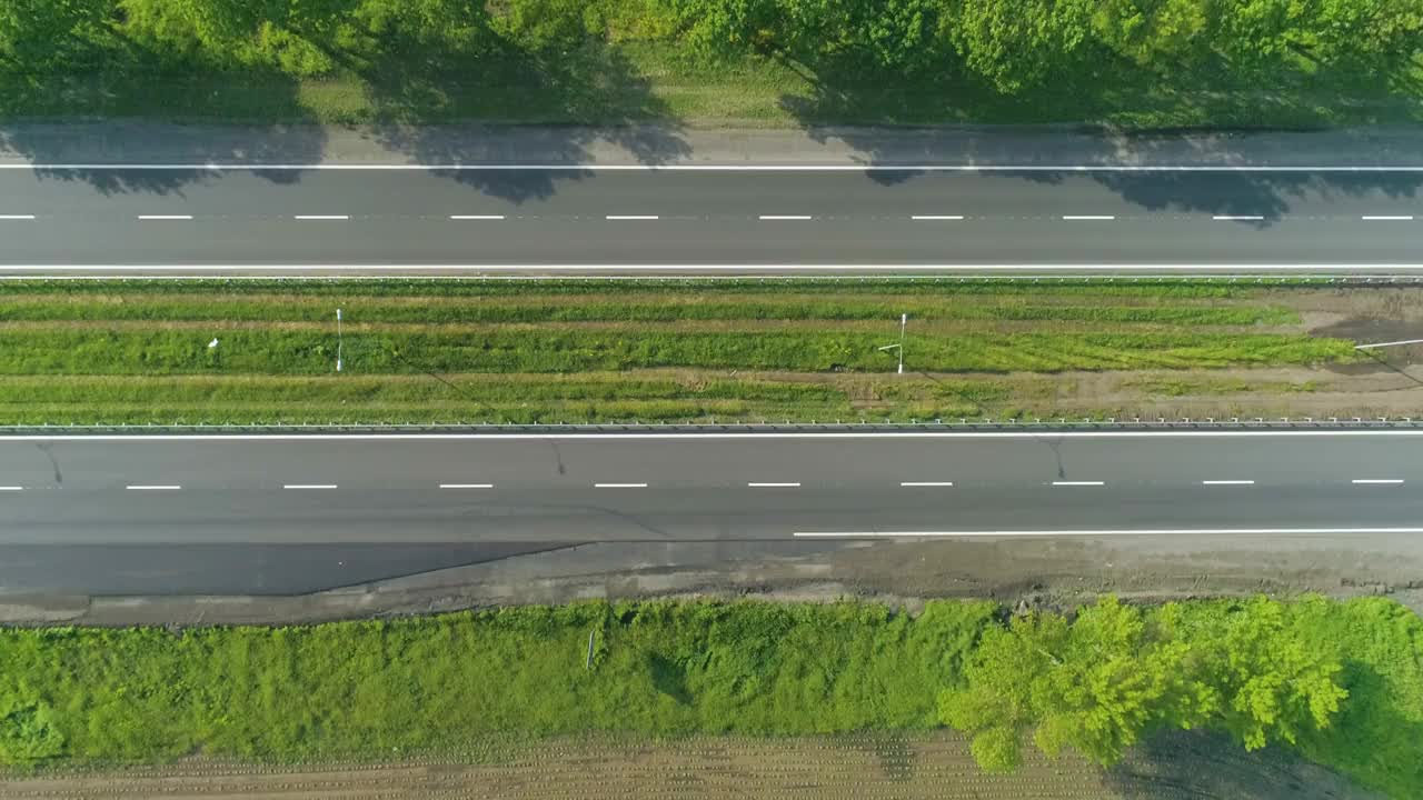 从无人机上看公路上的卡车。卡车在绿色草地周围的现代高速公路上行驶视频素材