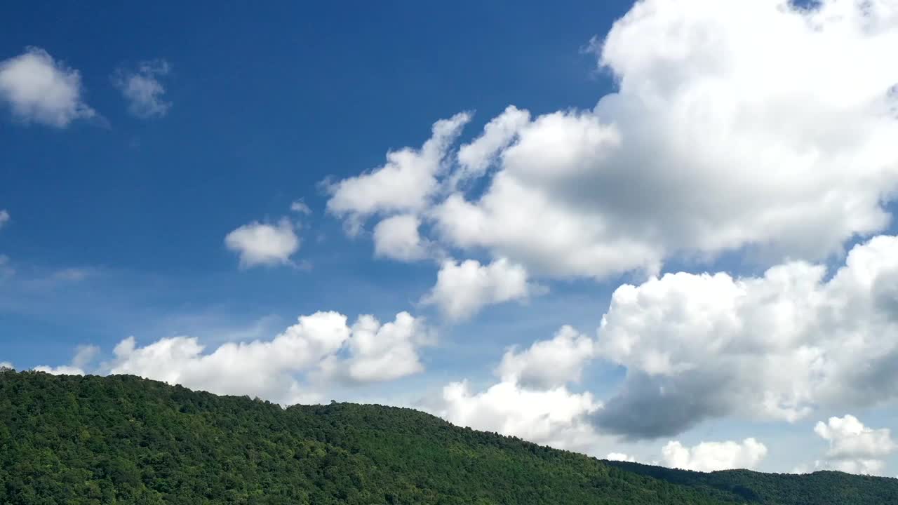 云流在热带雨林山顶反对春天的几个月的蓝色天空视频时间推移无人机飞行视频素材