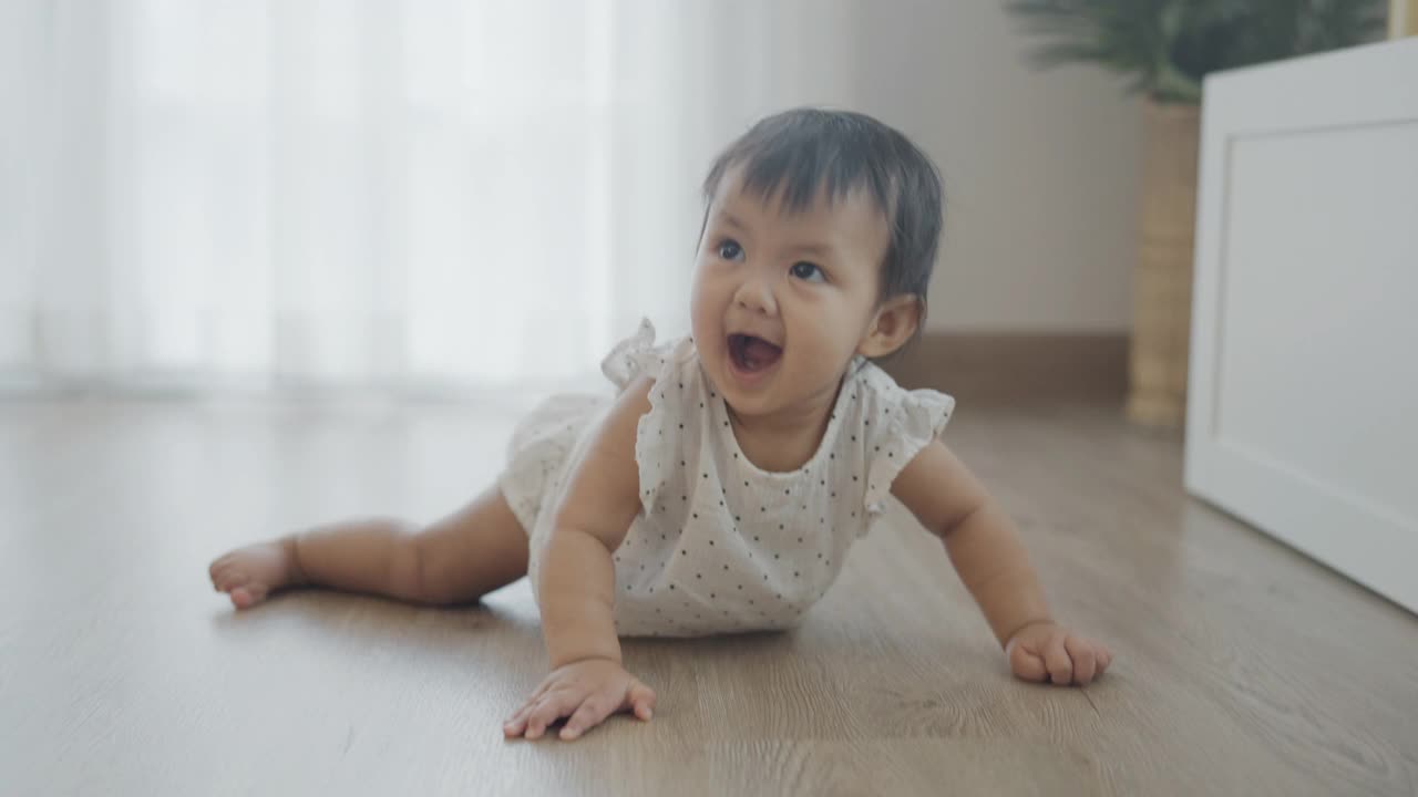 亚洲婴儿匍匐在家里的木地板上。视频素材