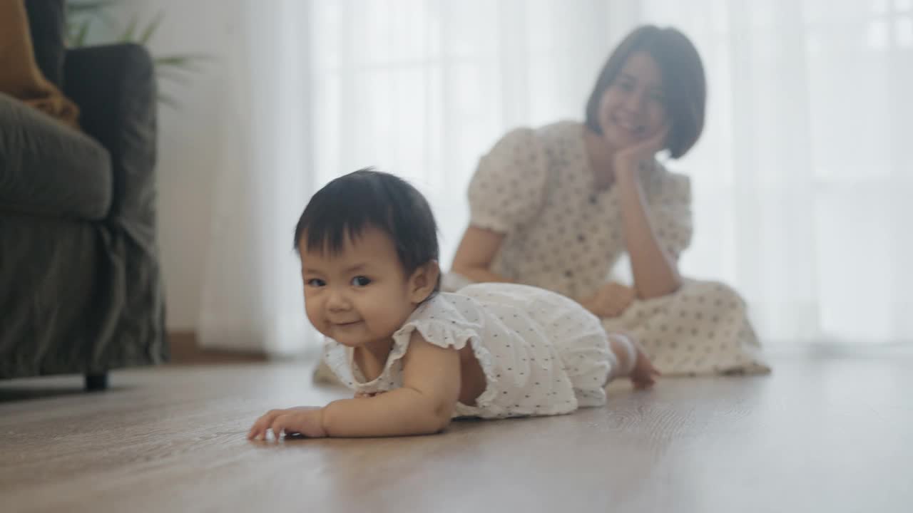 小女孩在房间的地板上爬着和年轻的妈妈视频下载