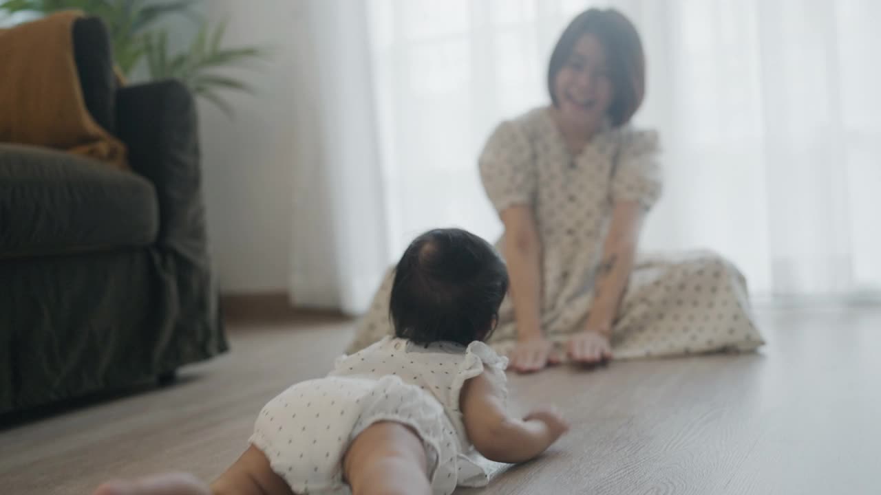 小女孩在房间的地板上爬着和年轻的妈妈视频素材