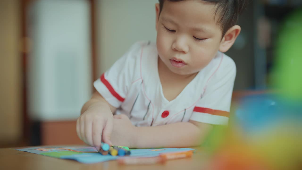 在新冠肺炎疫情期间，为了防止细菌传播，男婴们在客厅里用彩色笔画画。照顾孩子。视频素材