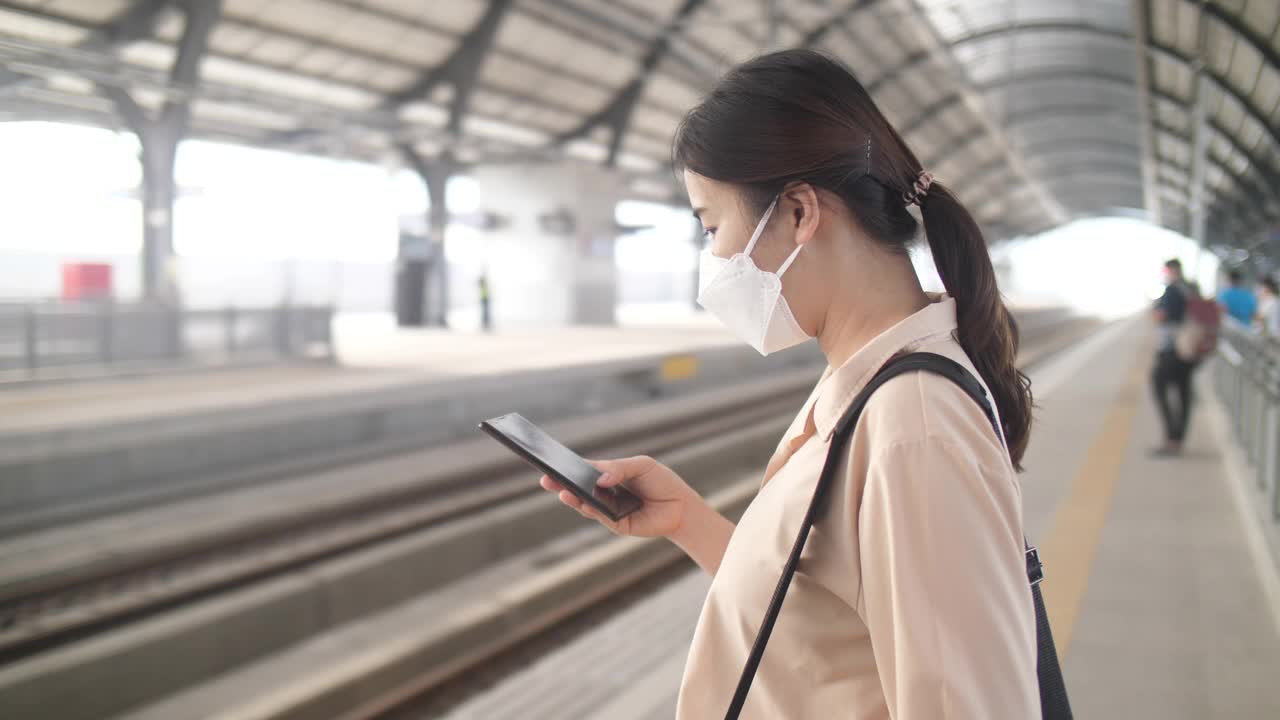 一名女子在曼谷火车站用智能手机等车视频素材