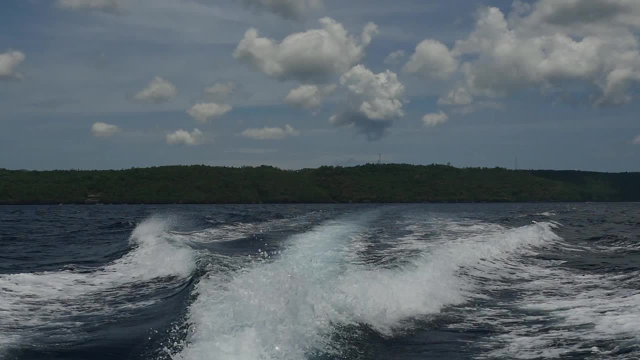 在印度尼西亚，一艘摩托艇发出的波浪以海洋地平线为背景。视频素材