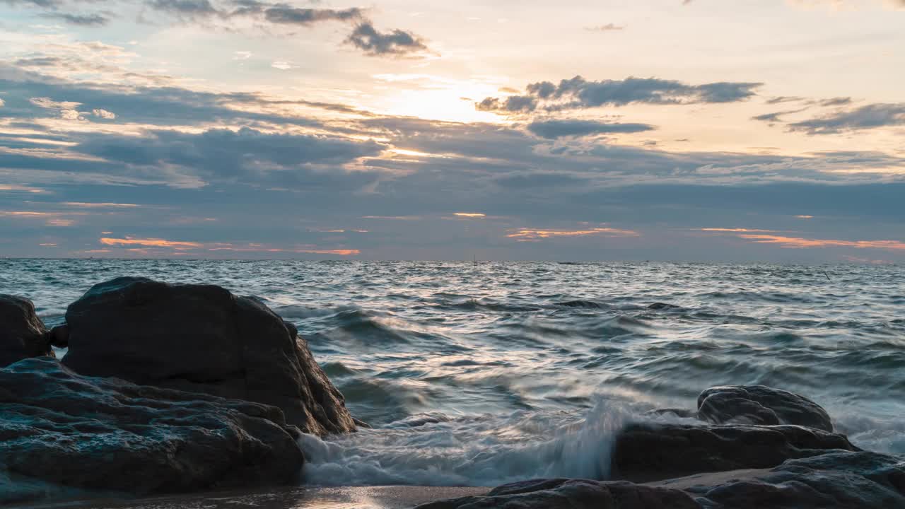 时间推移波浪击中岩石在日落海滩，日落云太阳在海上时间推移的镜头视频素材