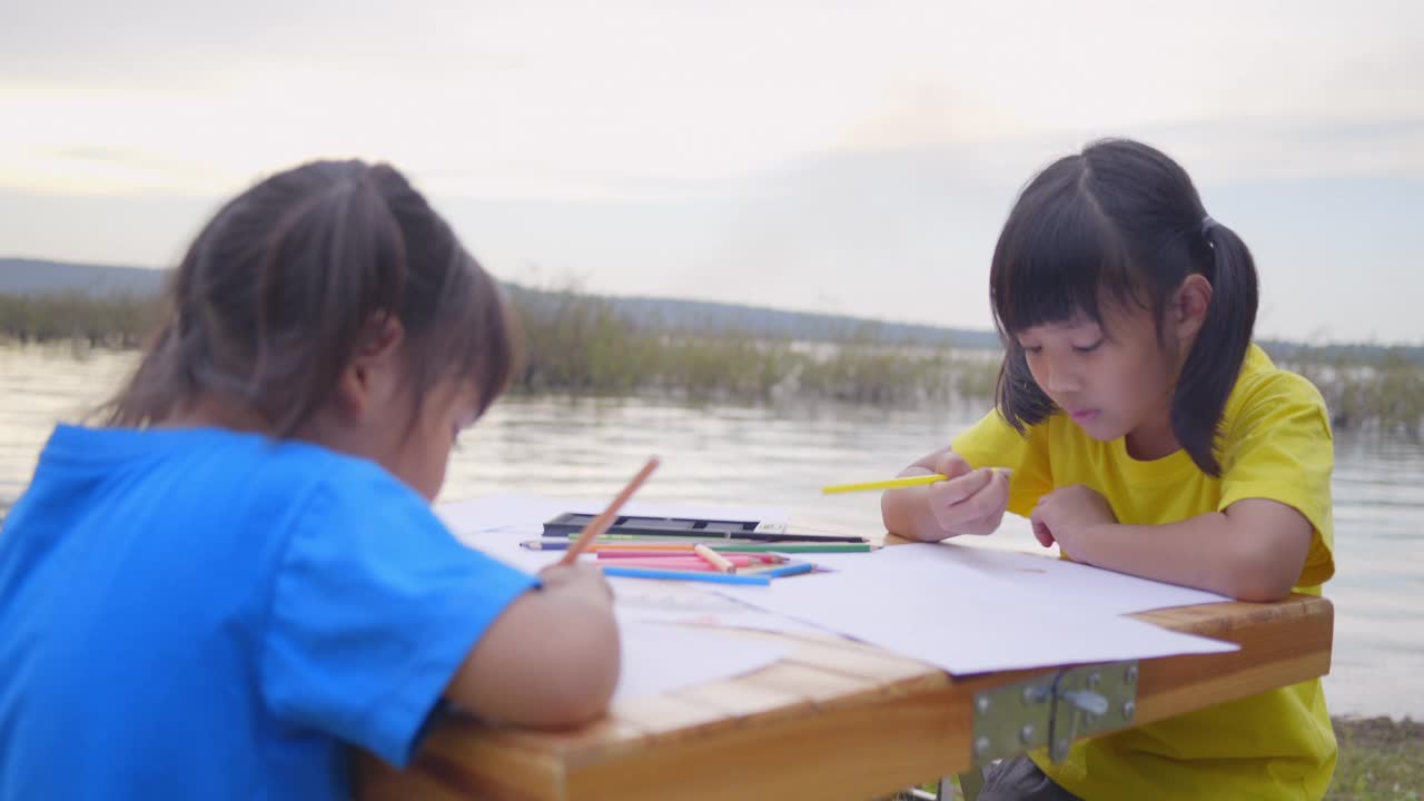 两个亚洲女孩在户外画画。亚洲兄弟姐妹笑着笑着幸福的成功视频素材