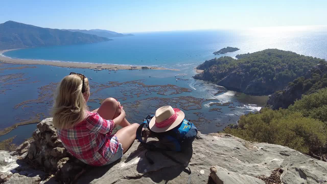 一个徒步旅行的女人坐在沙滩上看。视频素材