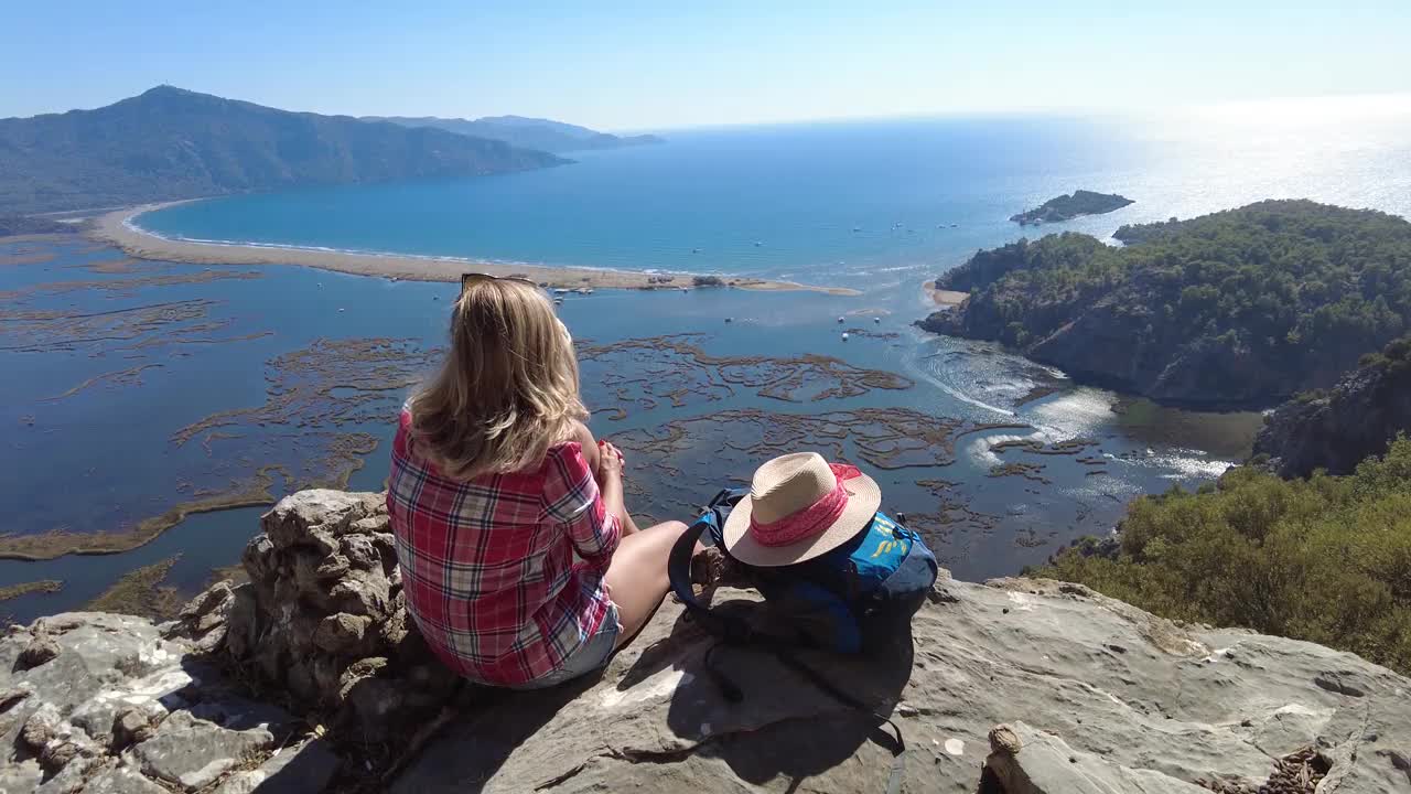 一个徒步旅行的女人坐在沙滩上看。视频素材