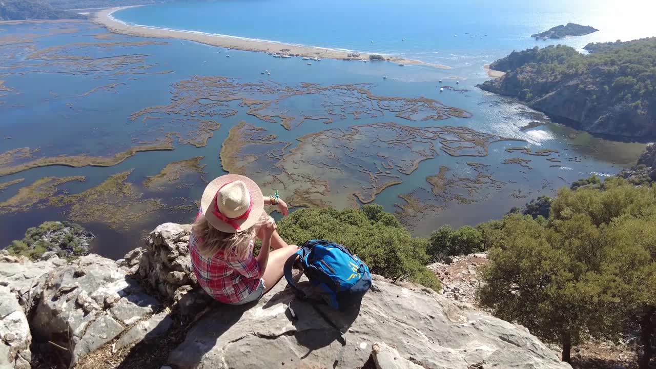 一个徒步旅行的女人坐在沙滩上看。视频素材