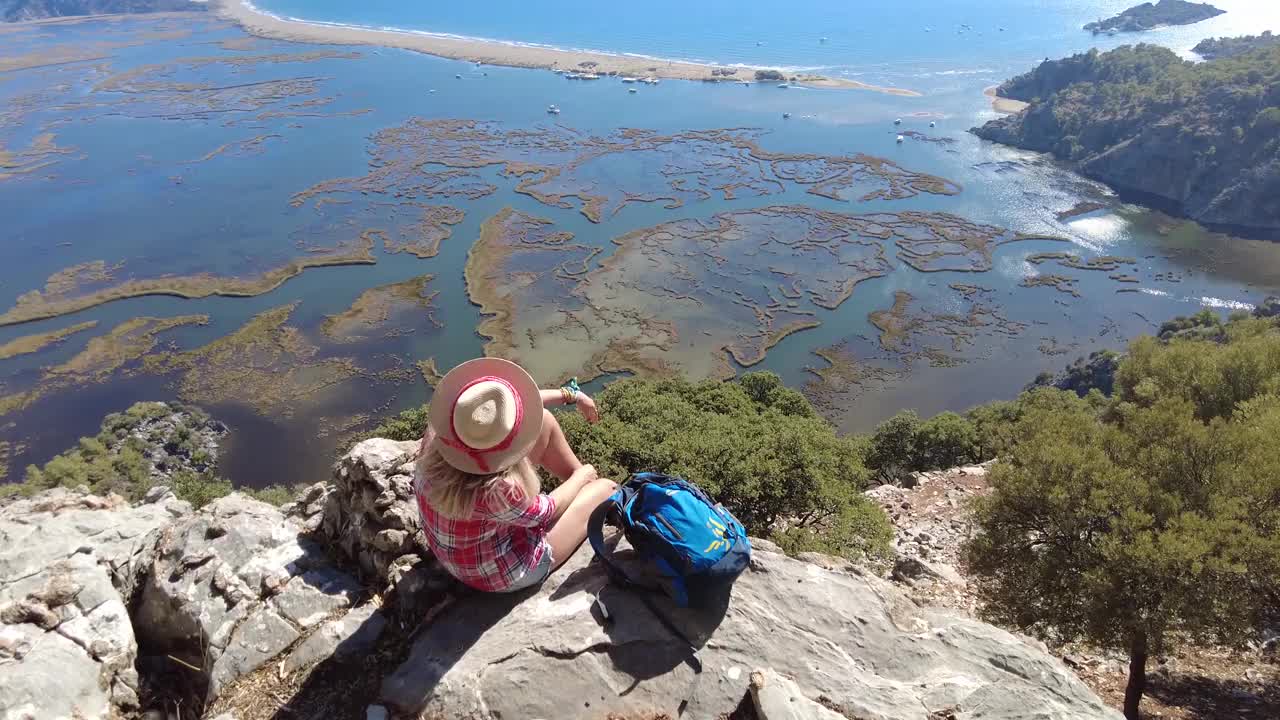 一个徒步旅行的女人坐在沙滩上看。视频素材