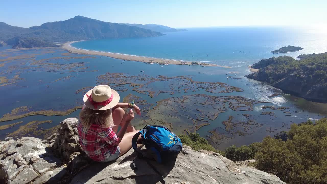 一个徒步旅行的女人坐在沙滩上看。视频素材