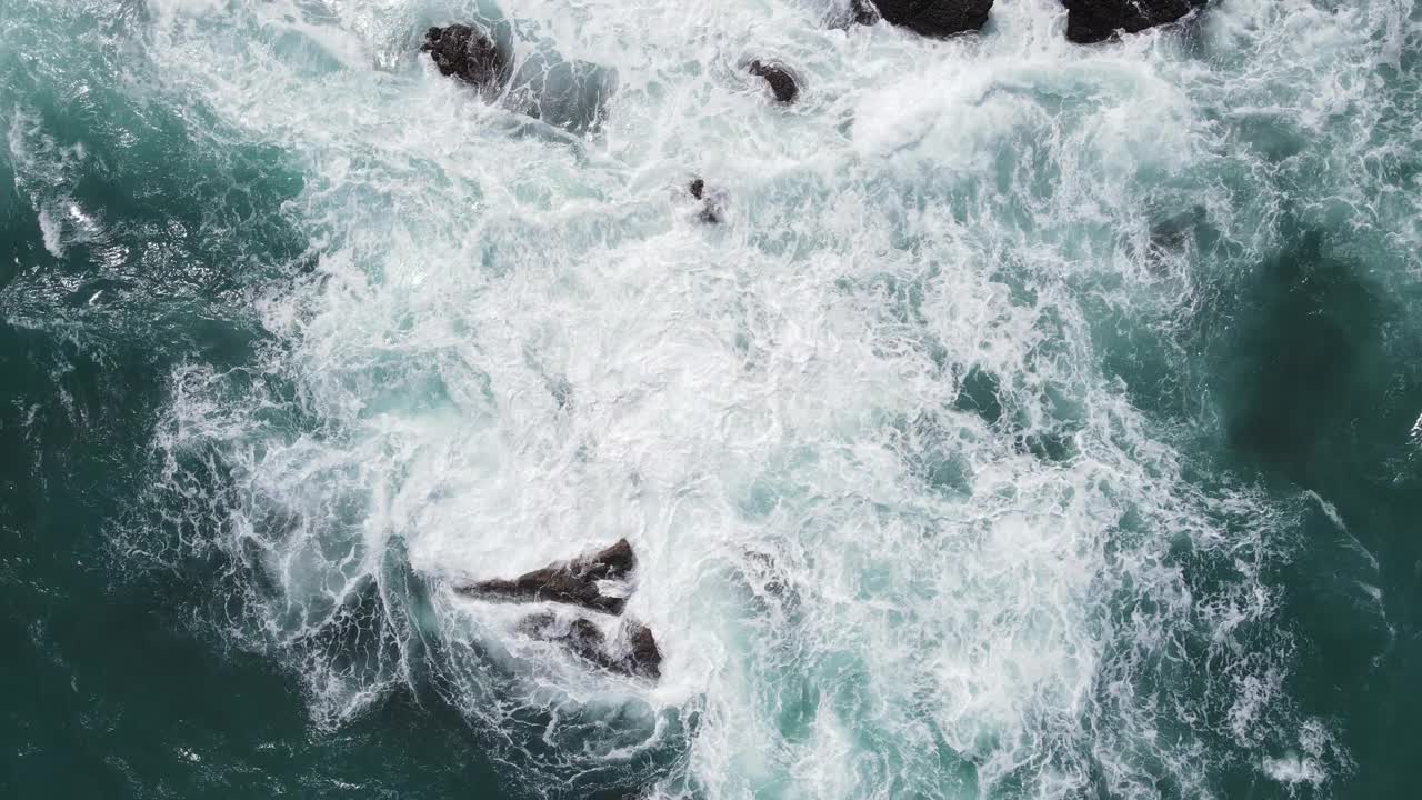 俯视图海浪撞击海岸的岩石，造成水的爆炸视频素材