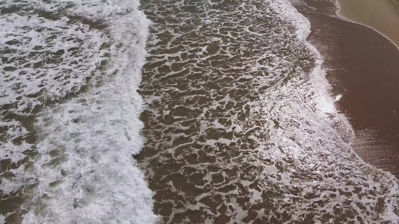 无人驾驶飞机在荒芜海滩上的海浪上飞行视频素材