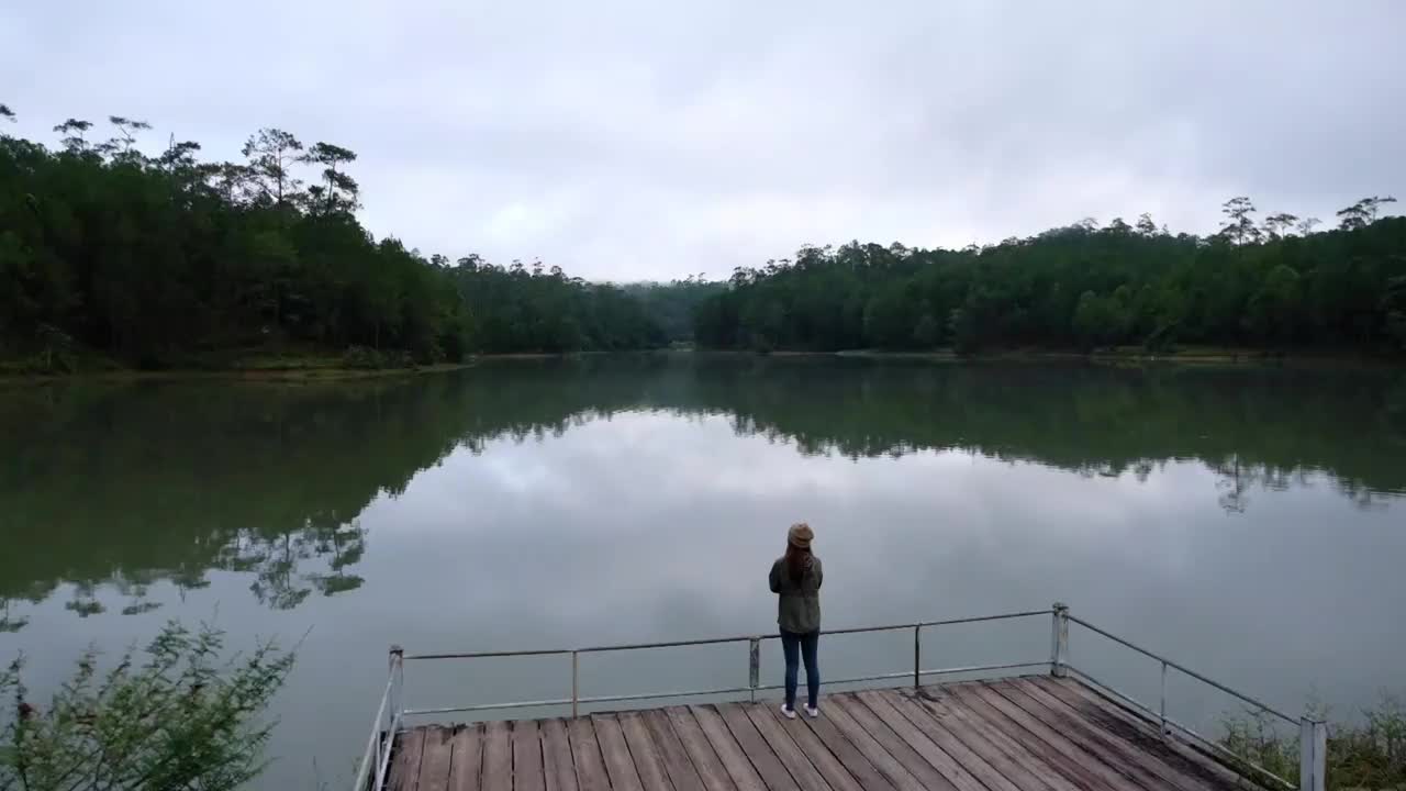 一位女游客在湖边欣赏美丽风景的慢动作视频素材