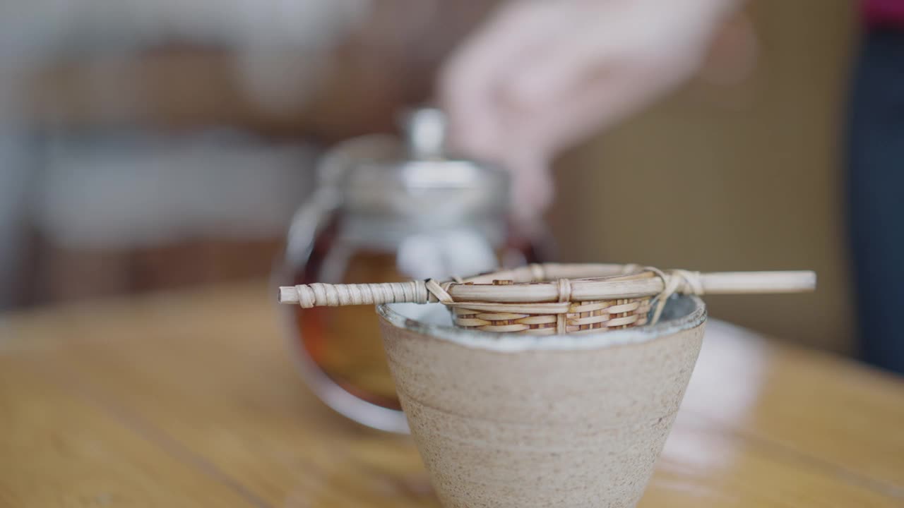 将茶倒进带有竹过滤器的杯子里视频素材