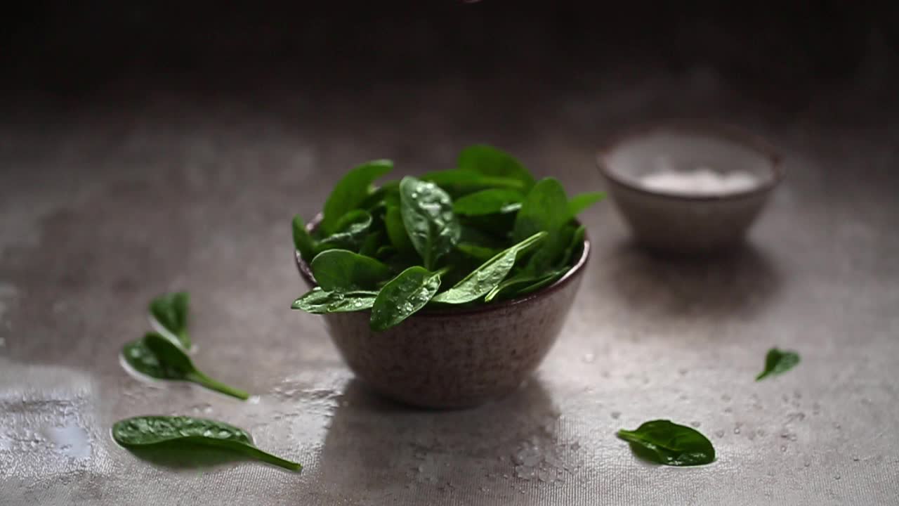 粗盐落在新鲜嫩菠菜叶子上的慢动作视频视频素材