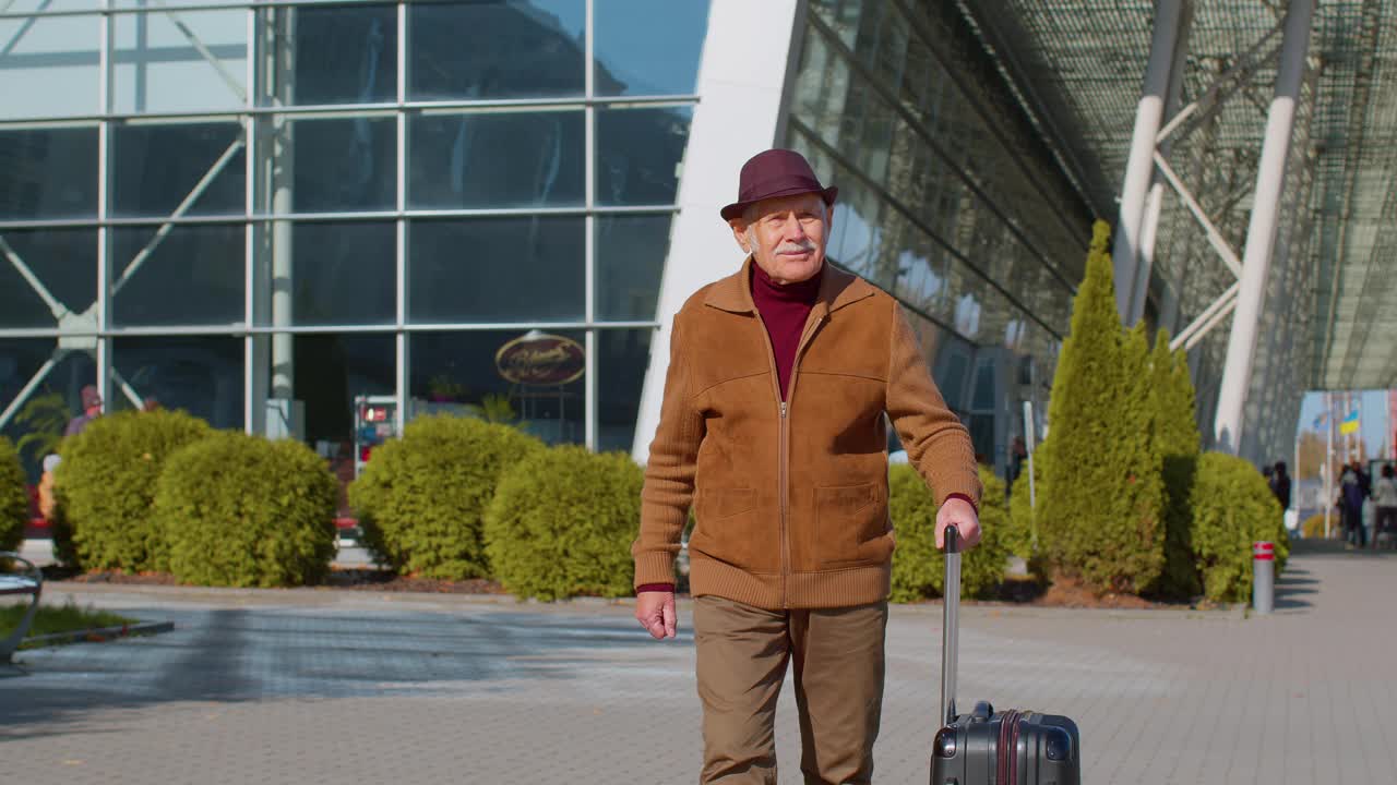 带着行李从机场大厅门口走出来的退休旅游爷爷商人视频素材