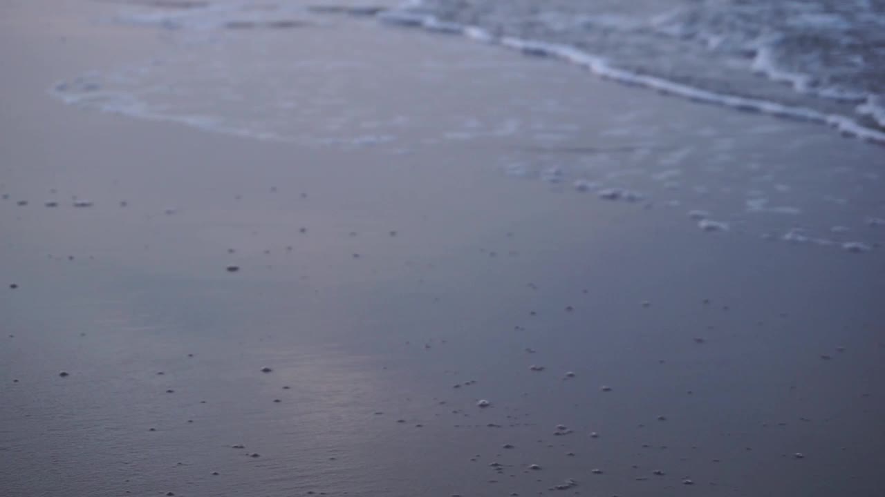 海浪冲刷着沙滩。日落时海滩会掀起波浪。视频素材