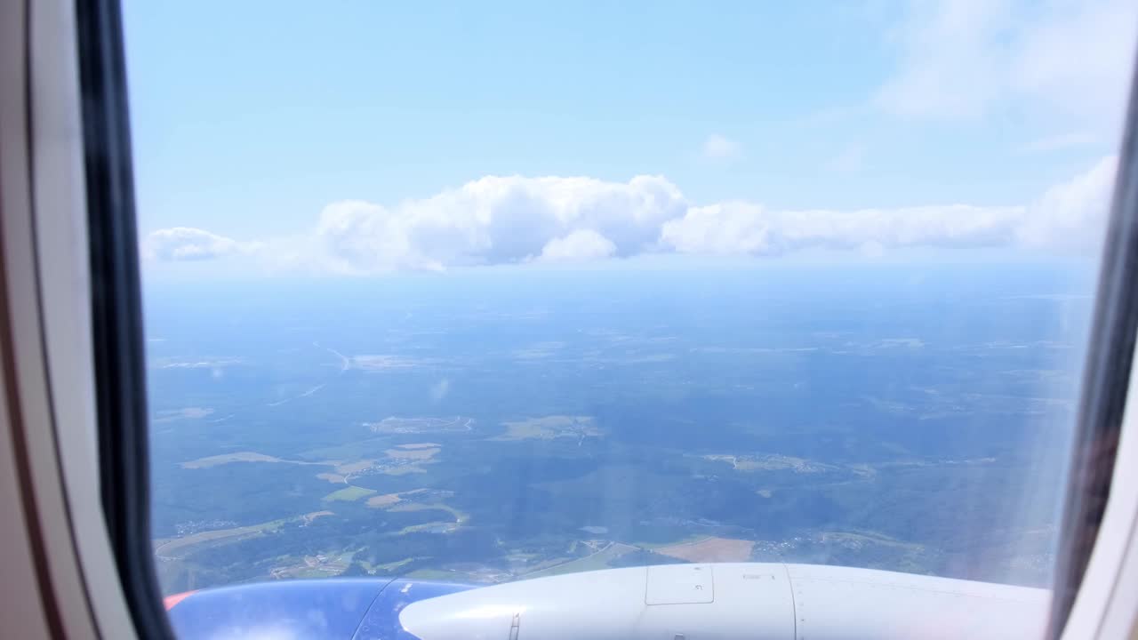 透过飞机的窗户看到的云和天空。概念飞行和旅行，从机翼上的飞机窗户看视频素材