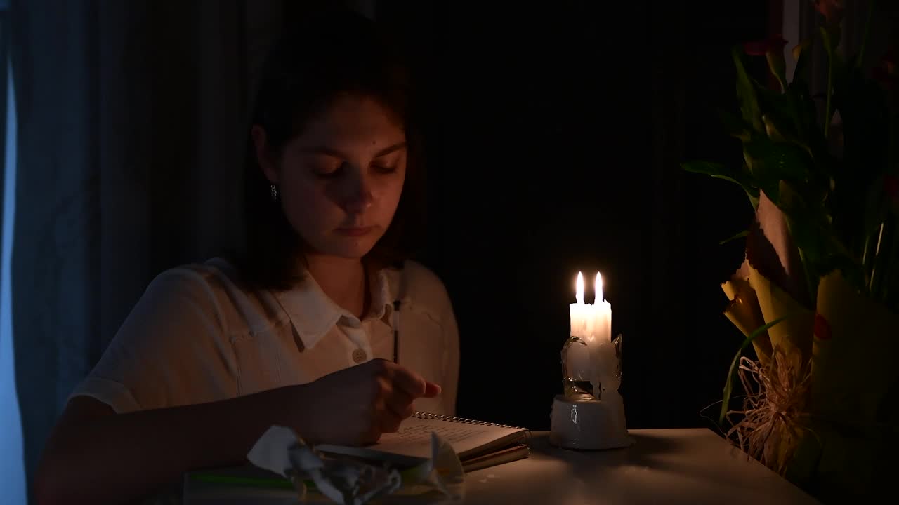 一个女孩在夜晚的烛光下写诗视频素材