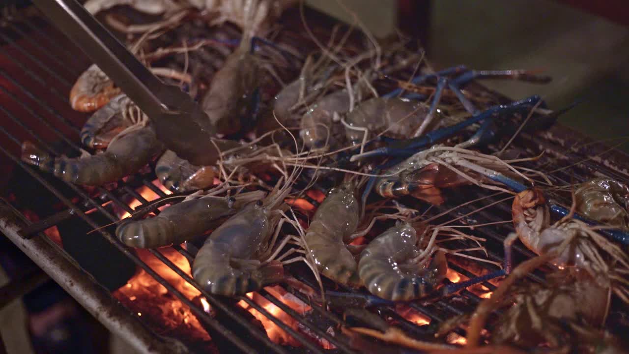 关闭烤架在热和红火烧烤新鲜的海鲜，虾在度假海滩晚餐派对视频下载