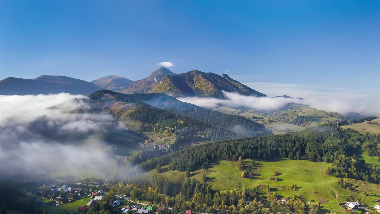 鸟瞰绿色的乡村景观在秋天的山与雾云运动在高山自然时间流逝视频素材