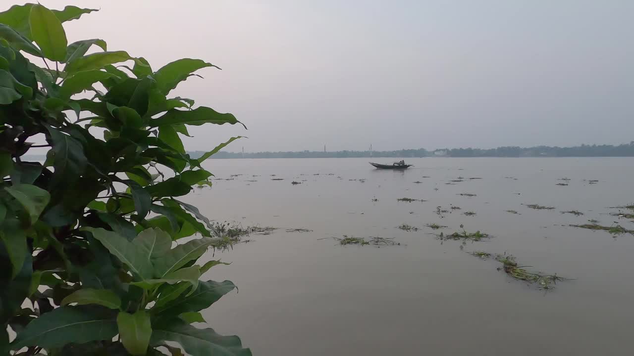 河流地平线景观在日落时对树枝在前景和晴朗的天空背景。远处有渡船驶过。视频素材