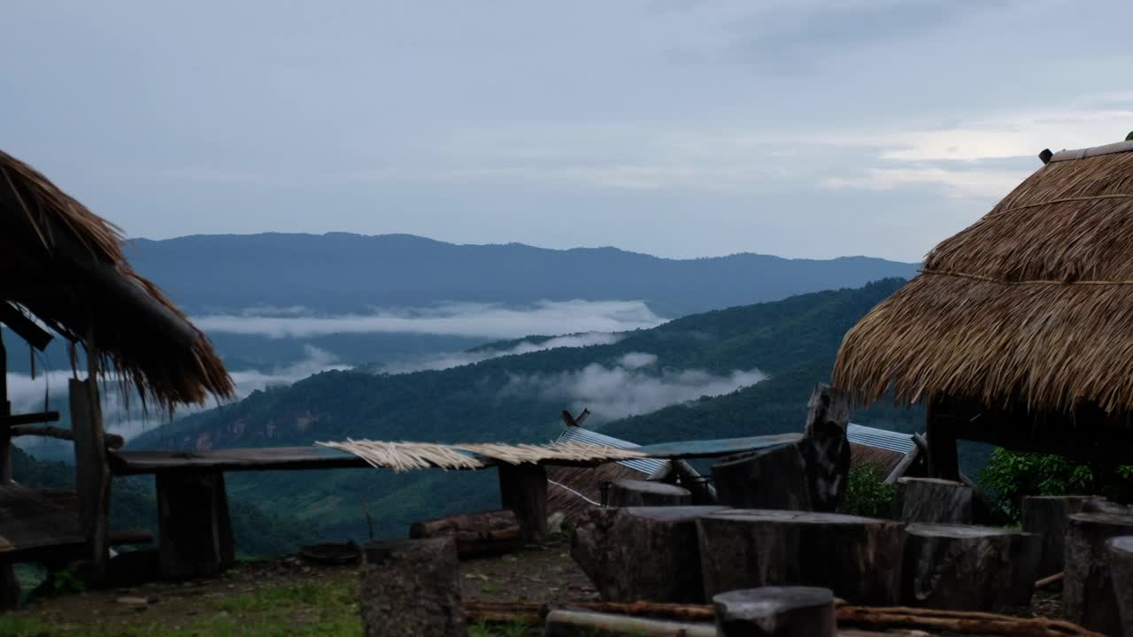 一位女旅行者坐在圆木上，看着美丽的山景视频素材