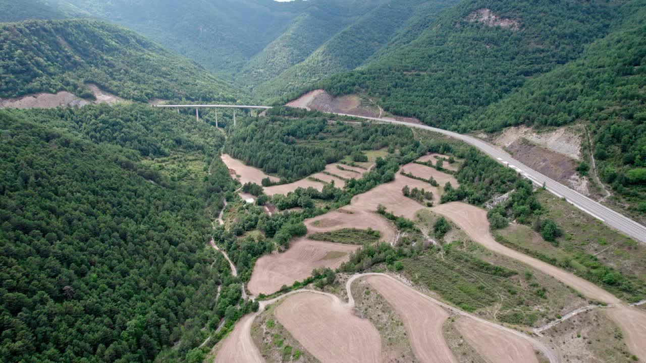 一座桥，一座山间的现代高架桥，一条三车道的柏油路。钢筋混凝土码头结构的桥梁连接两座小山，山上覆盖着森林。视频素材