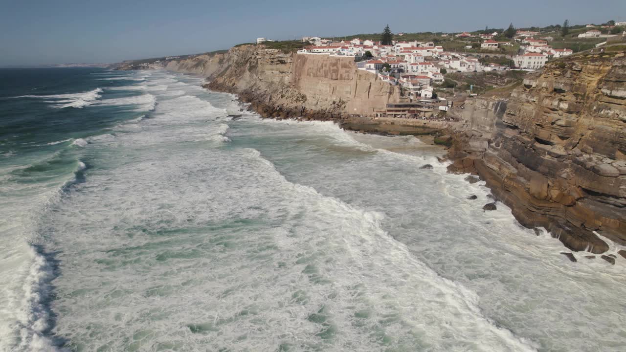 Azenhas Do Mar的豪华小镇坐落在高高的石崖边，海浪拍打着海岸线，无人机俯瞰视频素材